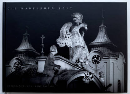 Cover des Buches "Die Nadelburg 2017" mit einer detailreichen Fotografie von Franz Baldauf, die eindrucksvolle Skulpturen und Architektur zeigt.