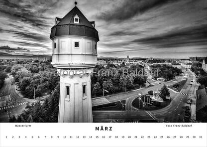 Schwarz-weiß Fotografie des Wasserturms in Wiener Neustadt im März, mit Blick über die Stadt und dramatischen Wolken am Himmel, die architektonische Schönheit und das Stadtbild betonen.