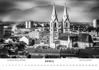 Schwarz-weiß Fotografie der Innenstadt von Wiener Neustadt im April, mit dem Liebfrauendom im Vordergrund und dem Schneeberg im Hintergrund, die eine beeindruckende Stadtlandschaft und Naturschönheit darstellen.