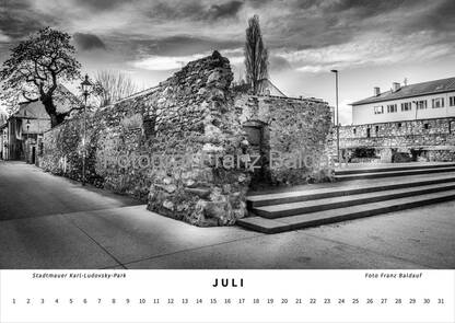 Schwarz-weiß Fotografie der alten Stadtmauer am Bürgermeistergarten Karl-Ludovsky-Park in Wiener Neustadt im Juli, die die historische Struktur und die ruhige Parklandschaft zeigt.